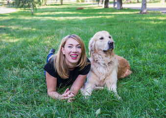 Wall Mural - young woman with her retriever lie on the grass in the park