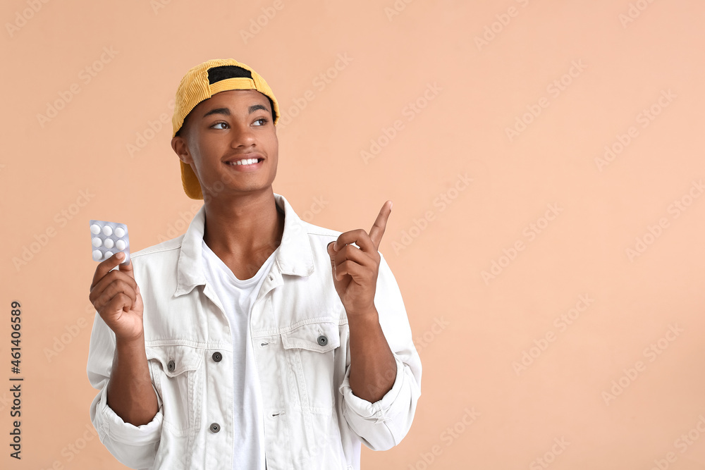 Young African-American guy with chewing gum pointing at something on color background
