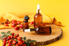 Composition With Bottles Of Essential Oil And Rose Hip Berries On Color Background