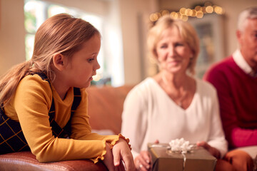 Wall Mural - Granddaughter With Grandparents Opening Gifts Around Christmas Tree At Home