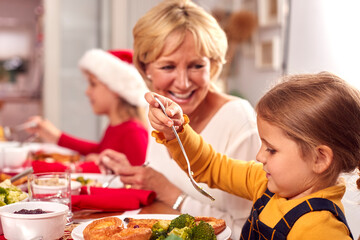 Wall Mural - Multi Generation Family In Santa Hats Enjoying Eating Christmas Meal At Home Together