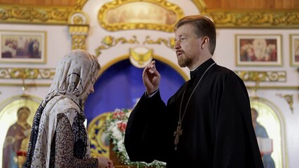 Wall Mural - a priest blesses a teenage girl in a headscarf in an Orthodox church after a festive church mass