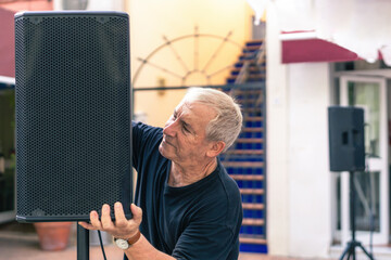 Musician setting up the speaker on a stage on a terrace