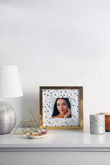 Sticker - Photo frame with portrait of beautiful young woman near stylish decor on white table