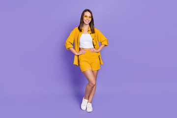 Wall Mural - Full size photo of cute young brunette lady stand wear eyewear yellow suit isolated on violet color background