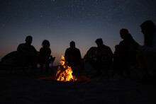Group Of Friends Gathering Around Bonfire In Evening. Camping Season