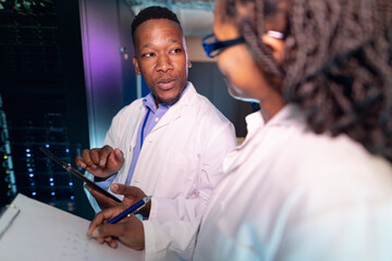 African american computer technicians using tablet working in server room