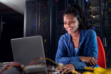African american female computer technician using laptop working in server room