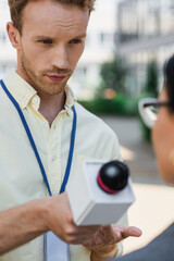 Wall Mural - reporter holding microphone near blurred businesswoman during interview