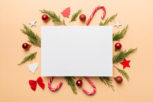 Flat Lay Christmas Composition. Square Paper Blank, Pine Tree Branches, Christmas Decorations On Colored Background. Top View, Copy Space For Text