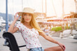 © Anatoly Repin - Woman in sun straw hat sitting on a wooden bench on Poros marina background, Greece