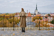 Blonde woman enjoy panorama of the city of Tallinn. Amazing scenic view of the old town. Girl explore Estonia, Europe. City and sea. City autumn landscape, old historical architecture.