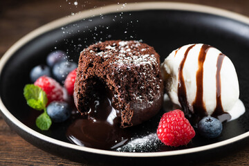 Wall Mural - Chocolate fondant cake, molten lava cake with ice cream scoop and fresh berries on plate