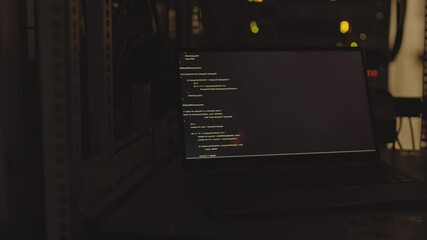 Locked-down of portable computer in dark room, computer code program running on screen