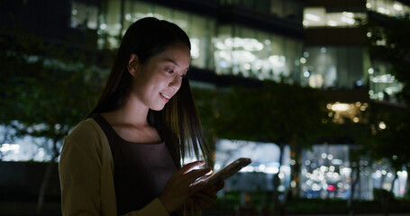 Wall Mural - Woman use of mobile phone with building background at night