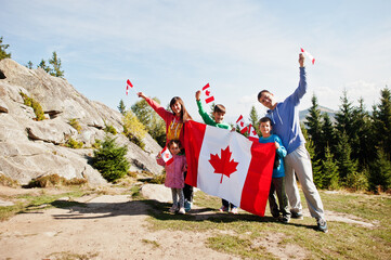 Happy Canada Day. Family with large Canadian flag celebration in mountains.