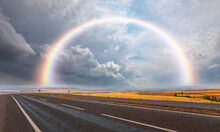 Asphalt Road Going Beyond The Horizon At The End Of The Path Amazing Rainbow With Stormy Dark   Clouds