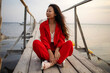 Beautiful asian woman wearing red suit sitting on old wooden pier