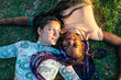 © Cavan Images - Multiracial female couple  lying on the grass. Lesbian couple