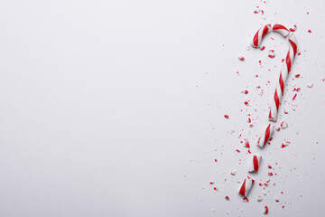 Poster - Broken sweet Christmas candy cane on white background, top view. Space for text