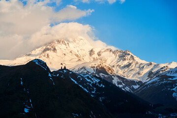 Wall Mural - Dawn in the mountains. The sun's rays fall on the top of Mount Kazbek. An inspiring morning for the traveler