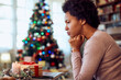 © Drazen - Worried African American woman thinks of something while spending Christmas alone at home.