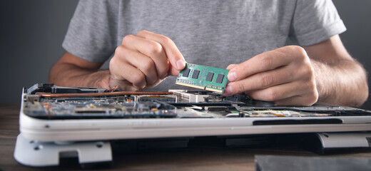 Technician installing random access memory on laptop computer.