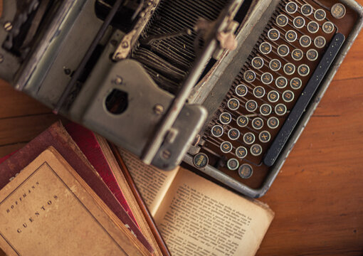 overhead photo showing open literature books and old vintage typewriter on wood table 