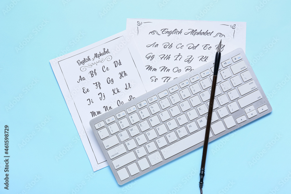 Paper sheets with alphabet, computer keyboard and brush on blue background