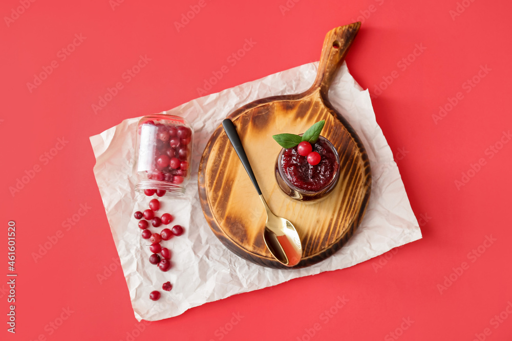 Board with tasty cranberry jam and berries on color background
