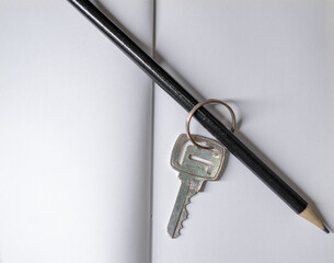 house key with black graphite pencil on white notebook. macro photograph with copy space