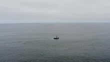 Drone Aerial Tracking Alongside A Lone Fishing Boat Going Out To See On A Cloudy And Calm Day.