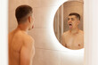 © sementsova321 - Indoor shot of young adult brunette male with naked upper body showing tongue in front of mirror in bathroom, doing morning hygienic procedures in the morning.