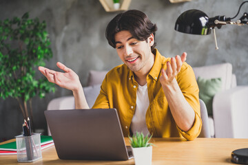 Sticker - Photo of cheerful friendly office worker guy sit desk laptop video call talk speak wear yellow shirt home indoors