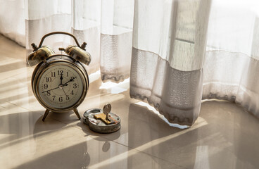 Alarm clock and Old vintage iron padlock is placed on the floor of the room that have early light through the beautiful curtain for background. Concept of light, hope and Value of time. Copy space, Se