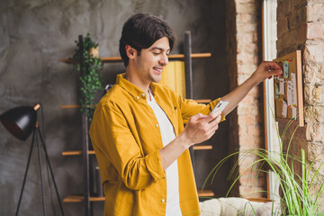 Sticker - Photo of positive nice businessman hold telephone browse surf internet blogging wear yellow shirt home indoors