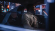 © Gorodenkoff - Stylish Black Man in Glasses is Commuting Home in a Backseat of a Taxi at Night. Handsome Male Passenger Looking Out of Window while in a Car in Urban City Street with Working Neon Signs.