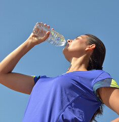  Young latin sport fitness woman drinking bottle water on outdoors blue sky background.