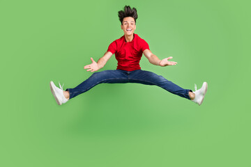 Wall Mural - Photo of pretty impressed young guy dressed red t-shirt jumping high smiling isolated green color background