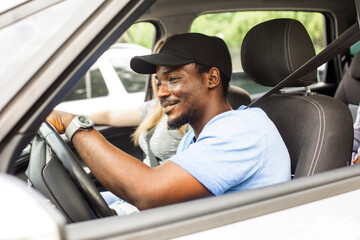 Cheerful young man driving car with friends on vacation