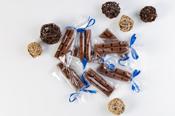 small packages with chocolate bars for a handmade gift on a white background with decorative balls