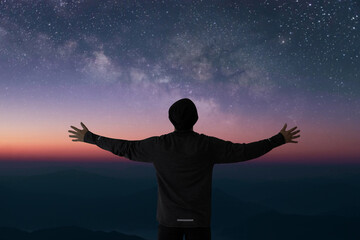 Wall Mural - Silhouette of young traveler and backpacker raise both arms and watched the star and milky way alone on top of the mountain. He enjoyed traveling and was successful when he reached the summit.