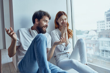 Wall Mural - boy and girl sit near the window with headphones together apartments