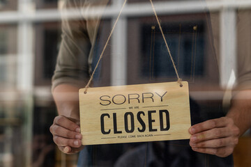 Close I. Barista A waitress turns a closed sign on a glass door in a trendy coffee shop. small business owner food and drink concept