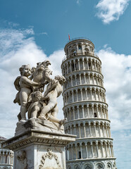 Monument with cherubs with background of the tower of Pisa in Italy 