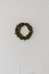 Wall Mural - Christmas wreath made of natural fir branches hanging on a white wall. Wreath with garland lights. New Year and winter holidays. Aesthetic Christmas decor