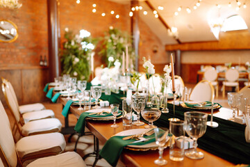 Wall Mural - Banquet table in the restaurant, the preparation before the banquet. The work of professional florists in emerald color. Wedding, birthday, party, event concept.