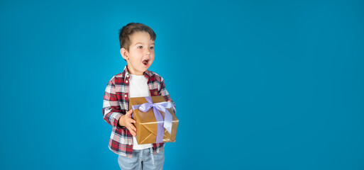 Wall Mural - Smiling boy holds present box and very surprised. Concept of holidays and birthday.