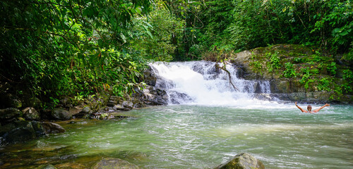 Woman bathing in a river by a waterfall. Costa Rica