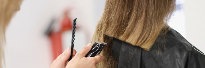 Wall Mural - Hairdresser doing hair cutting of woman using clipper in salon closeup